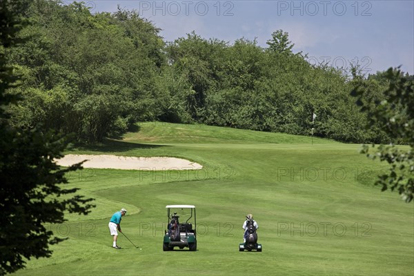 Pensioner with golf cart playing golf on fairway of golf course in Europe