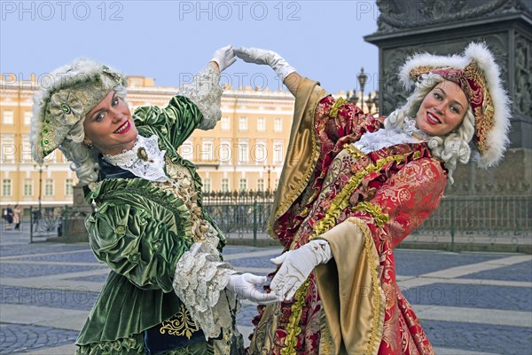 Two Russian women in 18th century period dresses posing for tourists by the Hermitage Winter Palace on Palace Square in the city St Petersburg