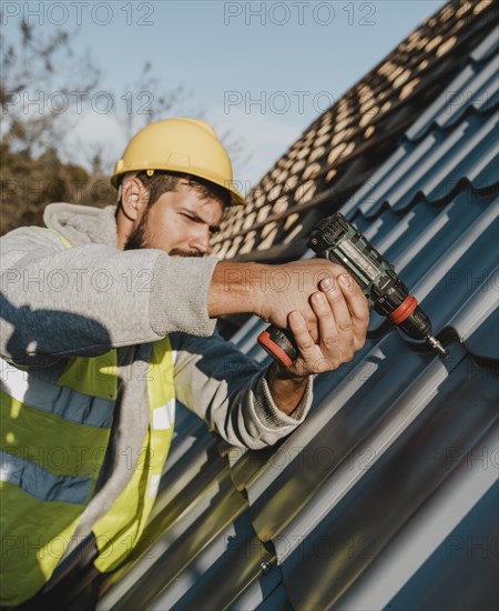 Side view man working roof with drill