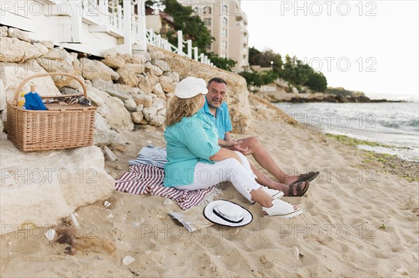 Side view elder tourist couple having picnic beach