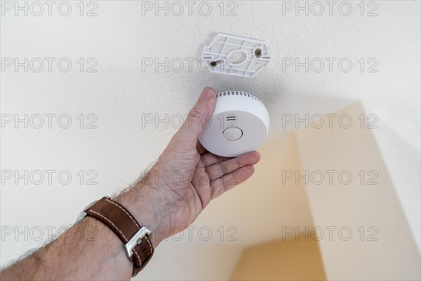 Man fitting domestic smoke alarm