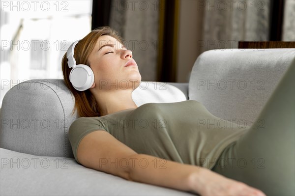 Medium shot woman couch with headphones