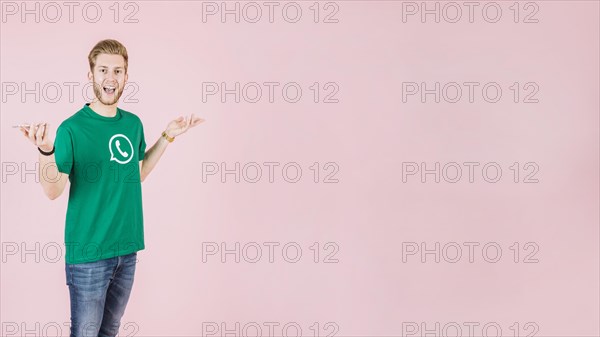 Portrait surprised man with smartphone pink backdrop