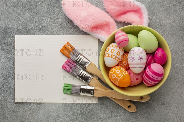 Top view colorful easter eggs bowl with paint brushes bunny ears