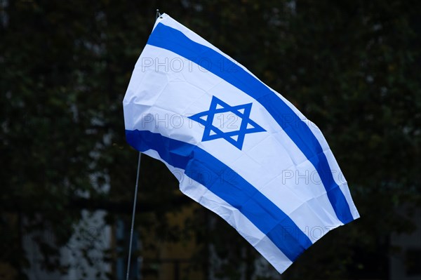 An Israel flag blows in the wind. Under the motto Never again is now