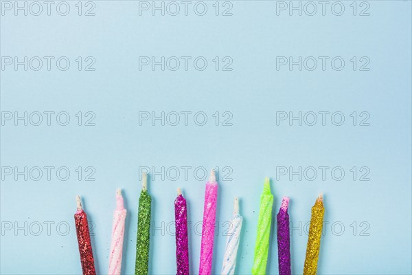 Row colorful sparkling candles blue backdrop