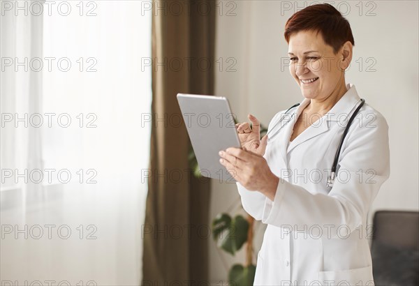Smiley elder covid recovery center female doctor with tablet stethoscope