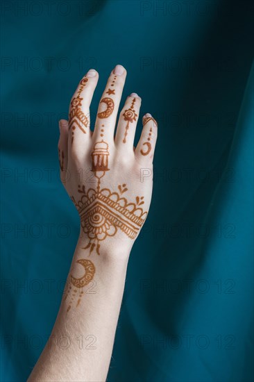 Woman hand with mehndi near blue textile