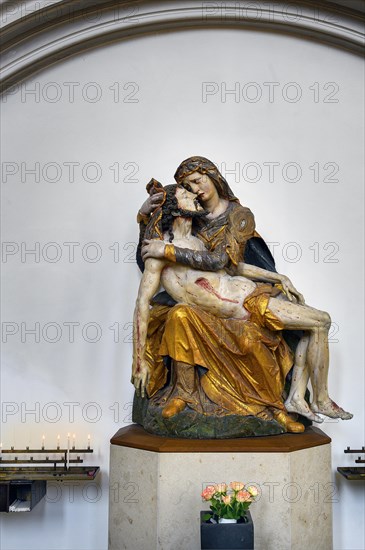 Pieta with sacrificial candles and floral decoration