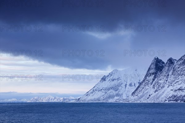 View over the Gimsoystraumen fjord and mountains in the snow in winter