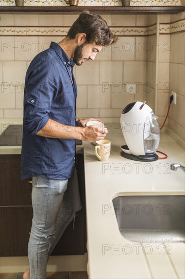 Young man standing kitchen preparing coffee