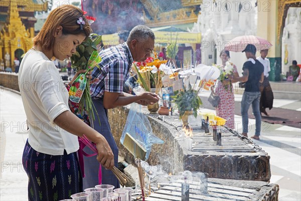 Burmese girl lighting incense sticks at the Shwedagon Pagoda