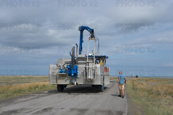 Man walking beside an amphibious vehicle on the road