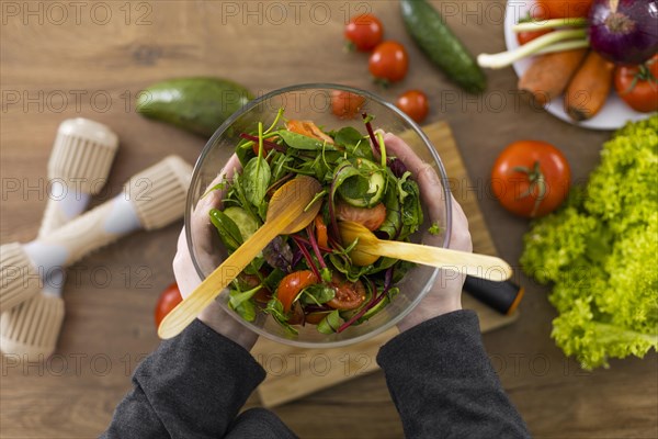Close up hands holding bowl with salad