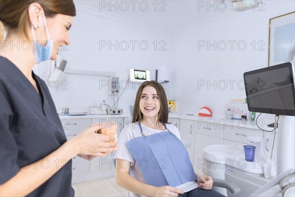 Female dentist showing teeth model smiling patient