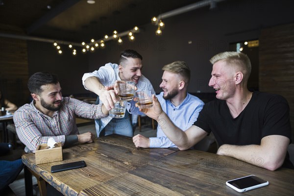 Happy friends cheering with whisky glasses bar