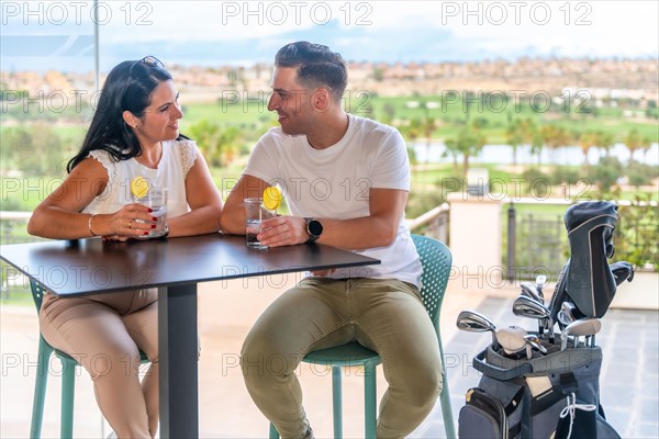 Happy couple enjoying a cocktail on a restaurant of a golf club