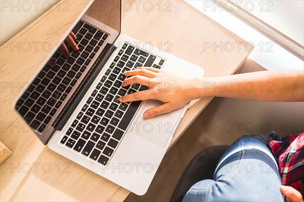 Top close-up of a woman working with laptop sitting at home