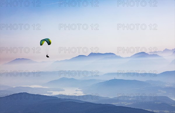 Paragliders high above the mountains with a view of the Klagenfurt basin and the Karawanken