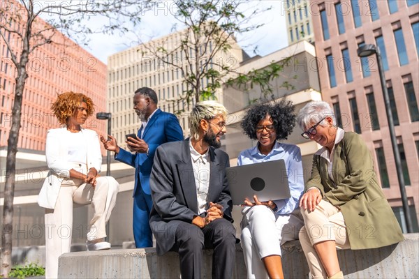 Multi-ethnic business people in an online meeting with laptop sitting on a bench outdoors