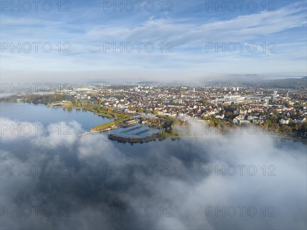 Aerial view of the town of Radolfzell on Lake Constance with autumn vegetation and drifting fog over the lake