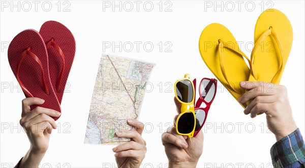 Hand holding travel items with flip flops sunglasses