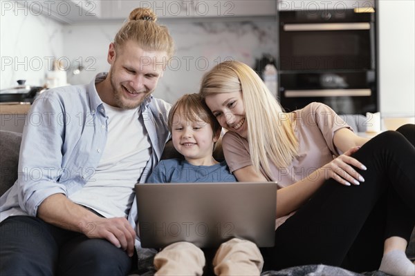 Medium shot smiley parents kid with laptop