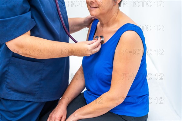 Cardiologist listening to the heartbeats of an older woman using a stethoscope