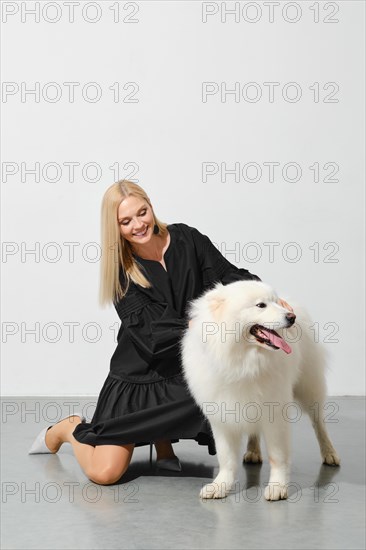 Happy blonde woman playing with her samoyed dog