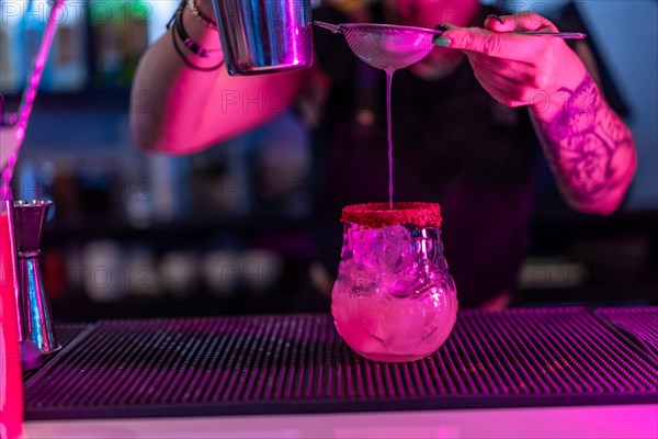 Close-up of a bartender preparing a cocktail with mixer and strain