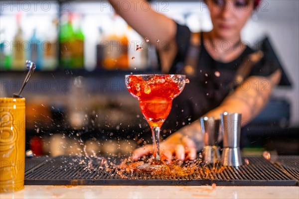 Cocktail splashing while bartender pouring the ingredients into a glass standing on a bar counter