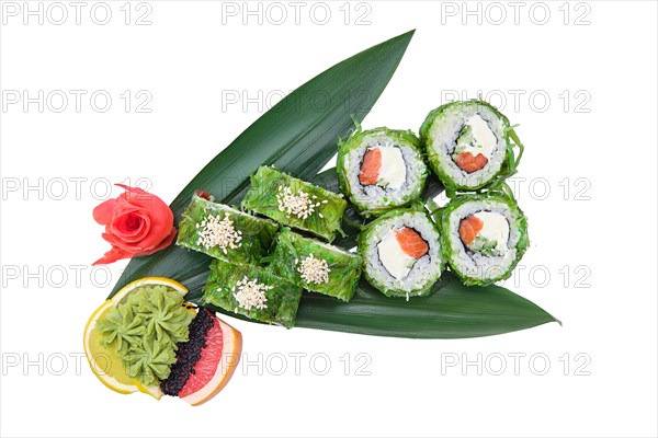Overhead view of sushi roll with salmon and chuka salad on top with cream cheese served on bamboo leaves