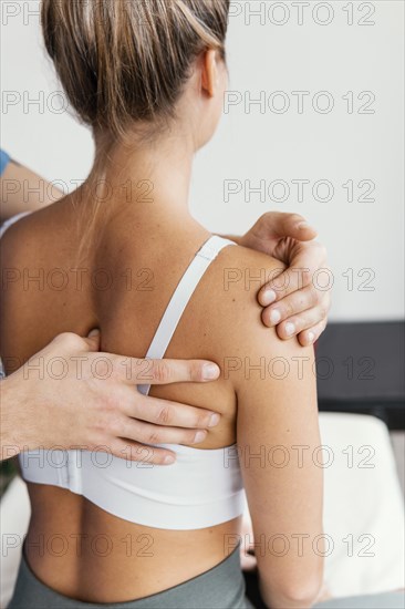 Male osteopathic doctor checking female patient s scapula