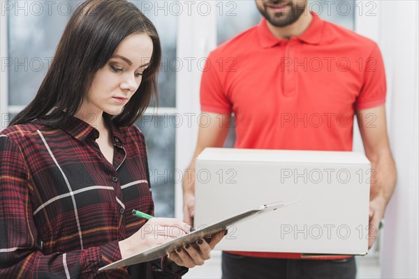 Woman signing receipt near crop courier