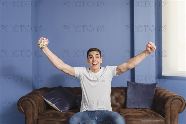 Football fan raising arms couch