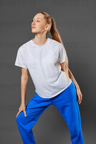 Young sportive woman bend forward over grey studio background