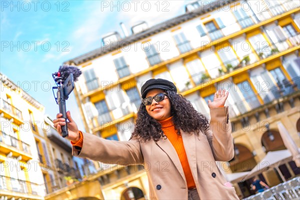 Latin influencer performing a life video using a mobile phone visiting a city in winter