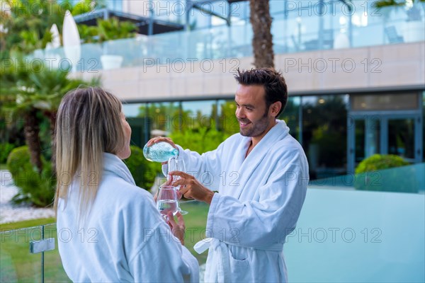 Relaxed couple drinking water in the terrace of a luxury hotel room