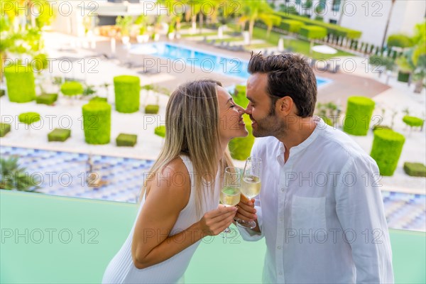 Newlywed couple kissing while toasting with champagne in the terrace of a luxury hotel