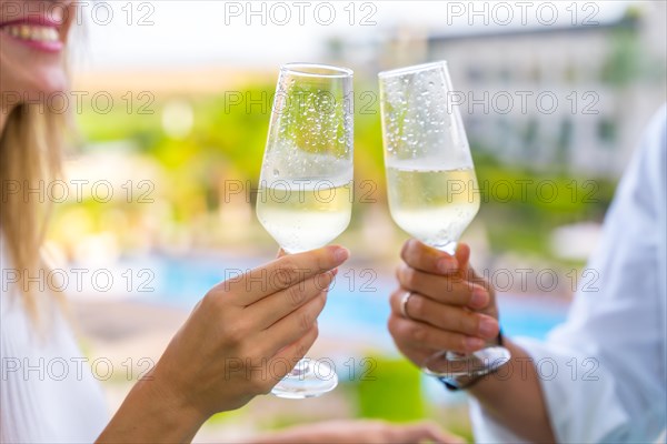 Close-up of hands toasting with champagne outdoors in a luxury hotel