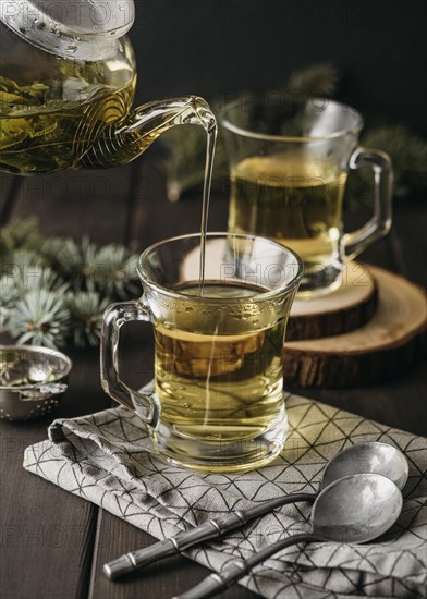 High angle hand pouring tea glass with teapot