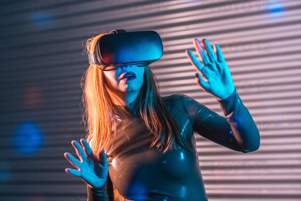 Shocked woman during an immersive game with Virtual reality goggles in an urban night space with neon lights