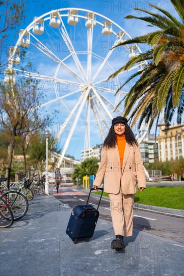 Vertical photo of a chic latin tourist arriving at a city with a Ferris wheel