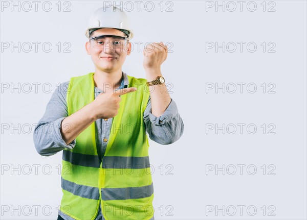 Smiling engineer pointing at his wrist watch isolated. Young engineer pointing and showing his wrist watch