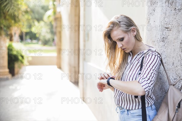 Close up blonde young woman checking her time watch