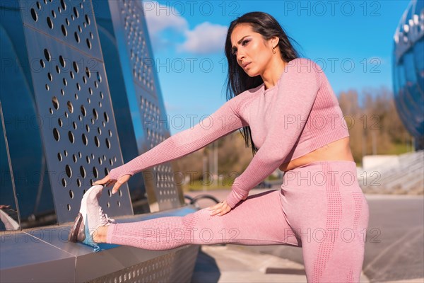 Concentrated woman stretching the leg in a park in the city