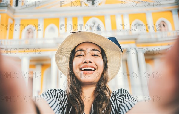 Smiling tourist girl in hat taking a selfie in a square. Lifestyle of tourist girl in hat taking a selfie in a square. Granada