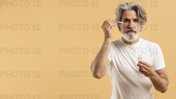 Front view senior bearded man applying serum