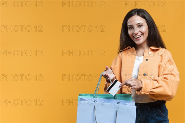 Smiley woman holding shopping bag credit card with copy space