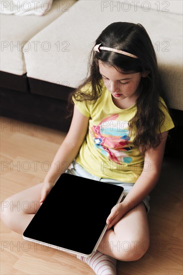 Full shot girl sitting floor with tablet